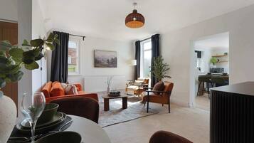 Een moderne woonkamer met een bank, fauteuils, een salontafel en een eethoek met een tafel gedekt voor twee personen.