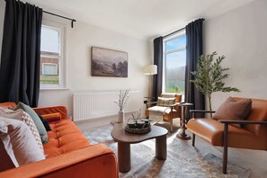 A modern living room with a sofa, armchair, coffee table, and a painting on the wall. - Spacious 4BR near Hornsea Museum | Sleeps 8+WiFi (Hornsea)