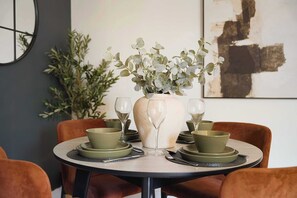 A dining table with a vase of green foliage, two wine glasses, and matching plates and bowls. - Spacious 4BR near Hornsea Museum | Sleeps 8+WiFi (Hornsea)