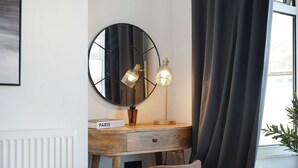 A room with a wooden bedside table, a round mirror, and two wall-mounted lamps. - Chic 4BR Near Hornsea Museum by Stay With Us (Hornsea)