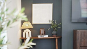 A modern living room with a dark wall, a framed abstract artwork, a lamp, a vase, and a small table labeled 'LONDON'. - Chic 4BR Near Hornsea Museum by Stay With Us (Hornsea)