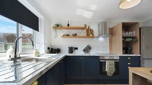 A modern kitchen with a large window, stainless steel appliances, and wooden cabinetry. - Chic 4BR Near Hornsea Museum by Stay With Us (Hornsea)