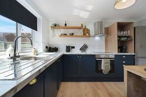 Eine moderne Küche mit großem Fenster, Edelstahlgeräten und Holzausstattung.
