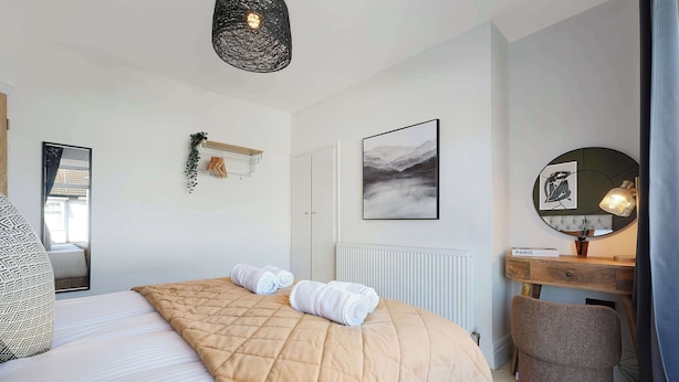 A bedroom with a bed, a bedside table, a mirror, a wall-mounted artwork, and a hanging light fixture. - Chic 4BR Near Hornsea Museum by Stay With Us (Hornsea)