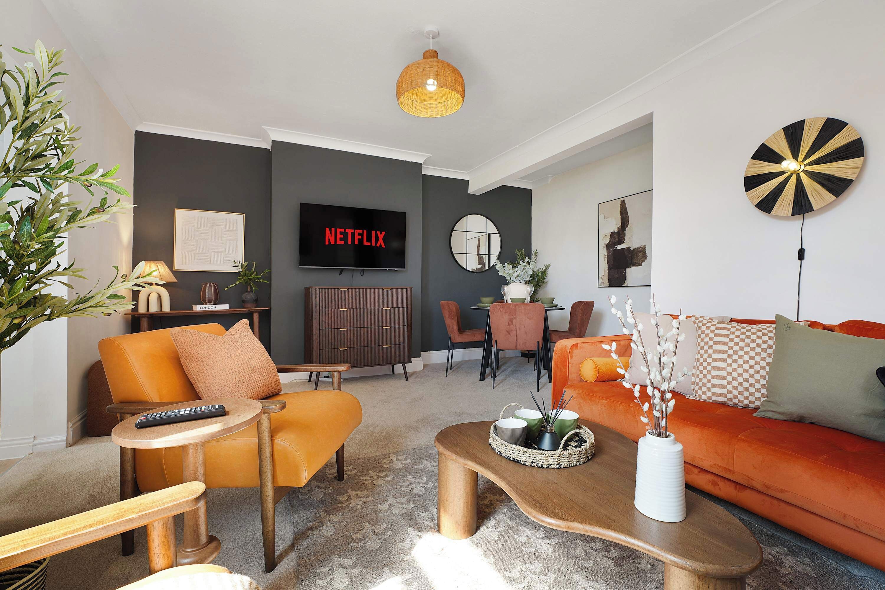 A modern living room with a sofa, armchairs, a coffee table, and a TV displaying the Netflix logo.