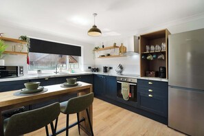 Une cuisine moderne dotée d’un îlot central, d’appareils électroménagers en acier inoxydable et d’une fenêtre offrant une vue agréable.
