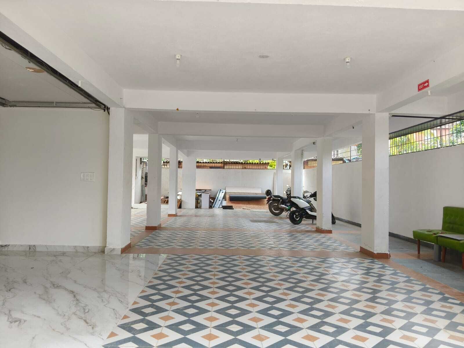 Um espaço amplo e interno com piso estampado, colunas e uma motocicleta estacionada.