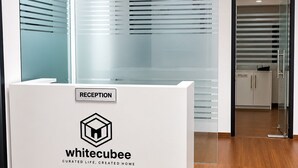 Una reception con il logo 'whitecubee' e la scritta 'RECEPTION', che dà accesso a un'area uffici con pareti in vetro.