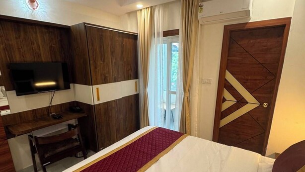 Una camera d'albergo con un letto, una scrivania, un televisore e una ventola a soffitto.