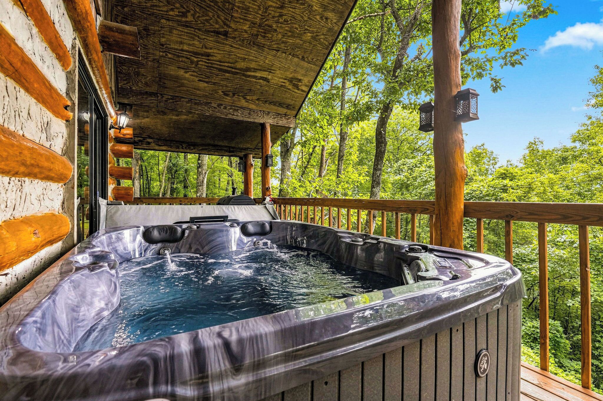 A hot tub on a wooden deck with a view of a forest.