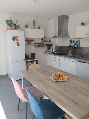 Eine moderne Küche mit weißen Schränken, einem Holztisch und verschiedenen Küchenutensilien.