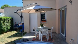 An outdoor swimming pool with a patio area, a table with chairs, and a small window with a potted plant. - Villa in Couleur 9 -bed (BRINDAS)