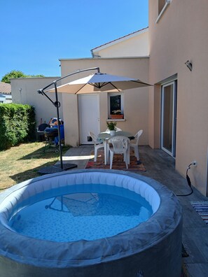 Ein Pool im Freien mit Terrassenbereich, einem Tisch und Stühlen sowie einem kleinen Fenster mit einem Blumentopf.