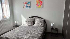 A bedroom with a bed, two nightstands, a window, and two wall art pieces. - Villa in Couleur 9 -bed (BRINDAS)