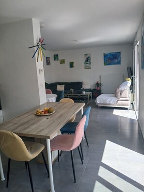 Ein modernes Wohnzimmer mit Essbereich, einer Couch und einem Sessel.