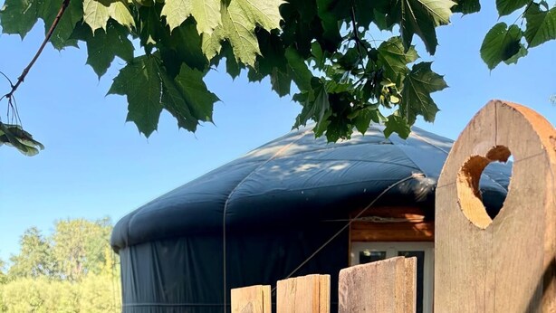 Una valla de madera con un hueco, una estructura cubierta y un sendero de madera.