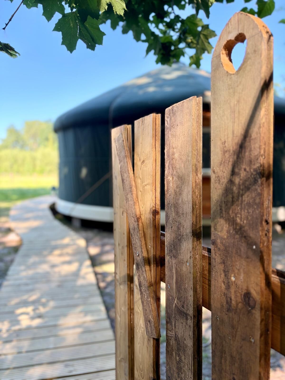 Une terrasse en bois qui mène à un grand espace extérieur aménagé avec des meubles de couleur sombre.
