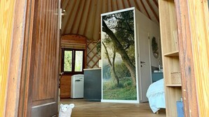 Interior de madera con un tragaluz circular, una escultura de oso blanco y un amplio ventanal con una vista de bosque.