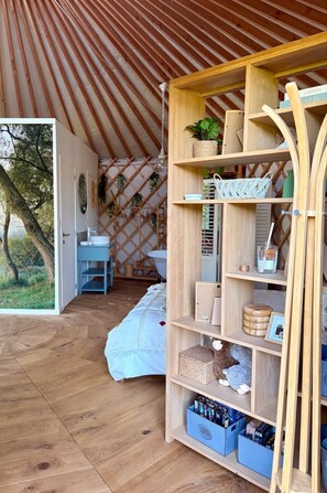 Een gezellige kamer met een houten boekenkast, een klein tafeltje en een bed met een witte deken.