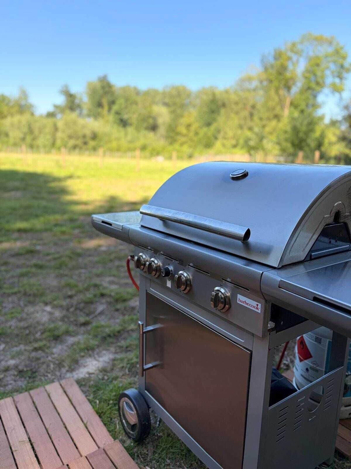A portable barbecue grill with a control panel and a storage compartment, placed outdoors on a wooden deck.