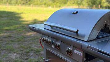 A portable barbecue grill with a control panel and a storage compartment, placed outdoors on a wooden deck.