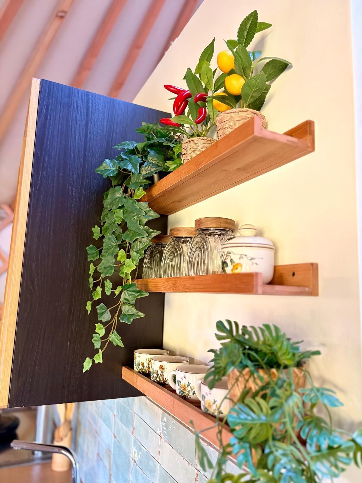 Una cocina con estantes de madera que exhiben plantas, frascos y utensilios de cocina.