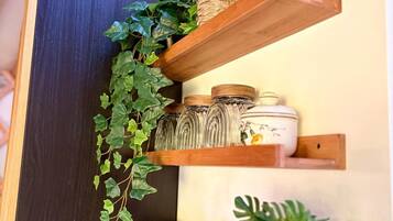 Una cocina con estantes de madera que exhiben plantas, frascos y utensilios de cocina.