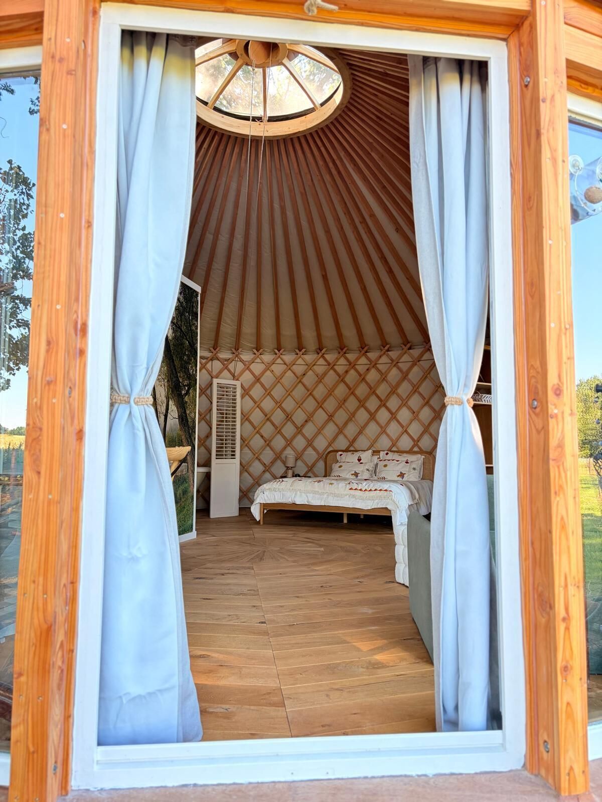 Una yurta con cama, cortinas y un ventilador.
