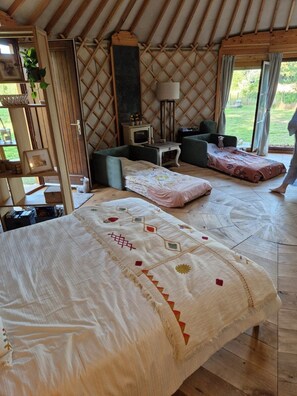 Ein gemütliches Zimmer mit einem großen Bett, einer kleinen Couch, einem Fernseher und einem Fenster mit Vorhängen.