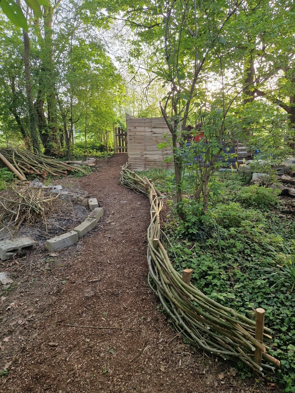 Un sendero de jardín con una cerca de madera y una verja que lleva a una construcción de madera.