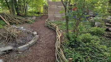 Un sendero de jardín con una cerca de madera y una verja que lleva a una construcción de madera.