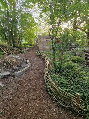 Een tuinpad met een houten hek en een poort naar een houten gebouw.