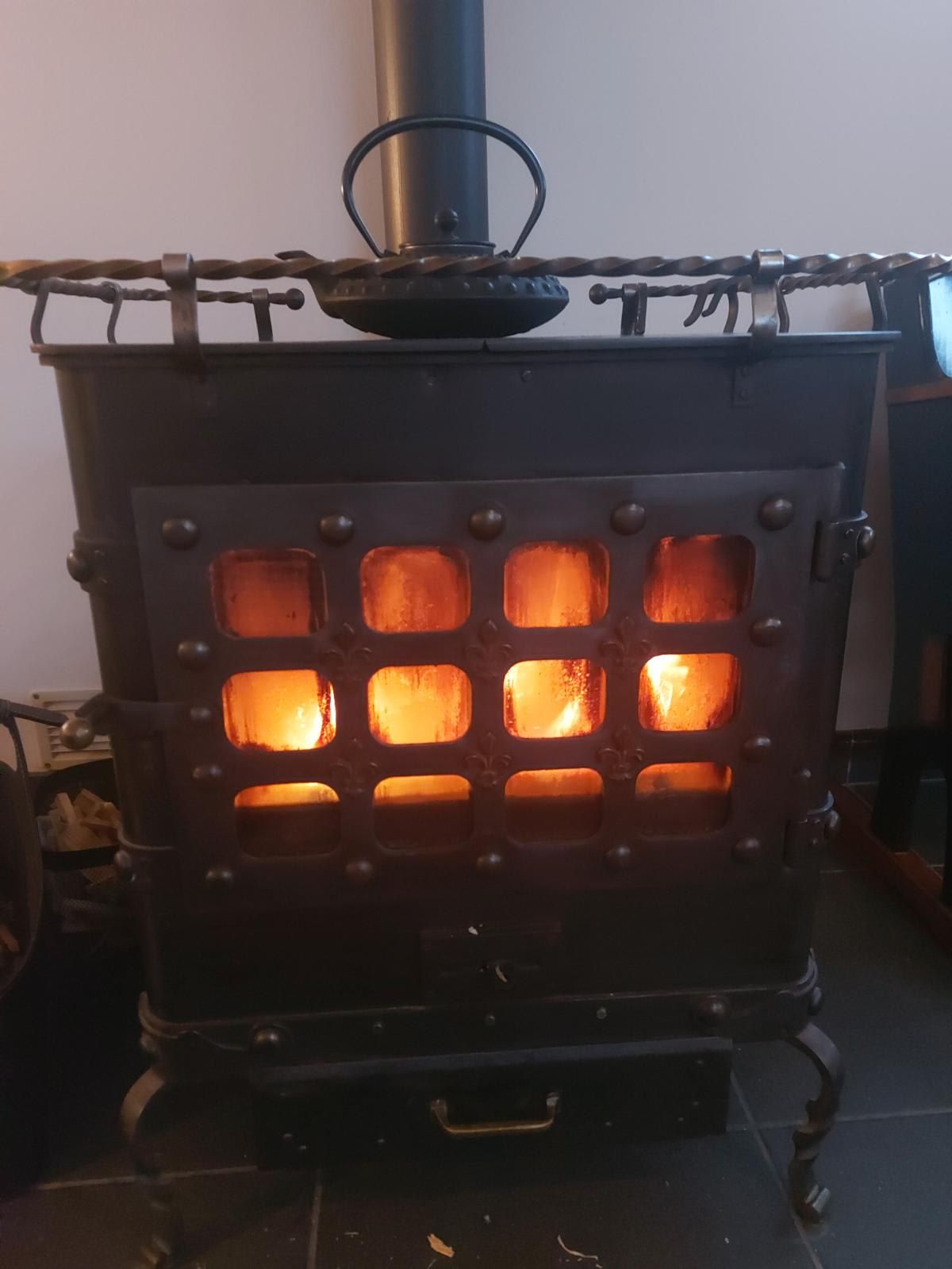 Una estufa de leña con una rejilla metálica y una chimenea.