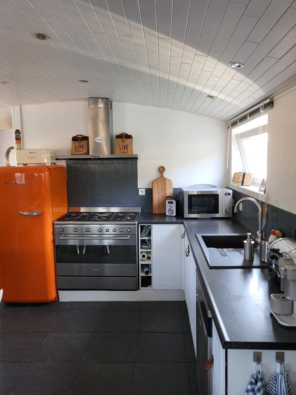 Een moderne keuken met een gasfornuis, oven, magnetron en spoelbak.