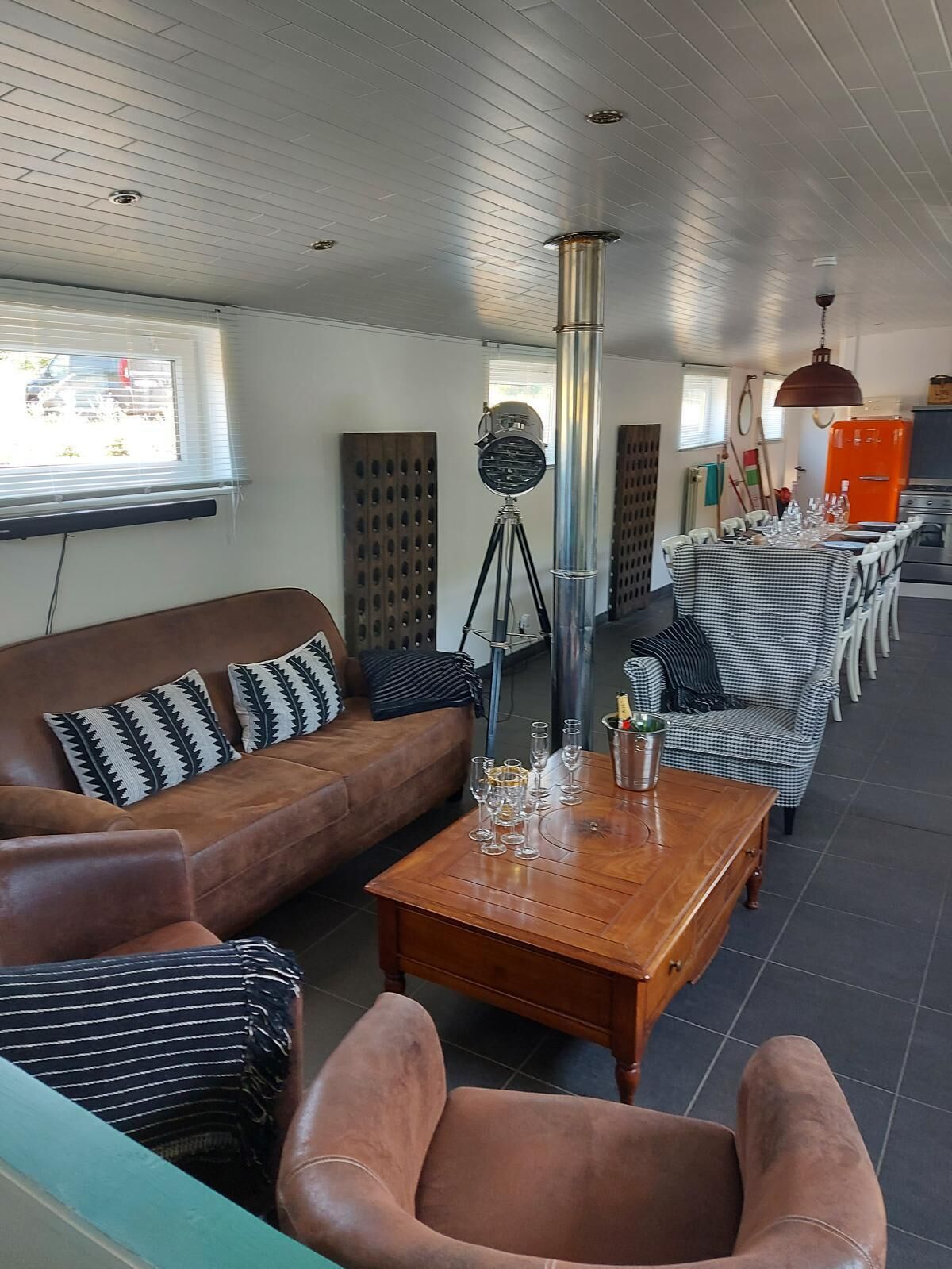 Een moderne woonkamer met een bank, fauteuils, een salontafel en een eetgedeelte met stoelen.