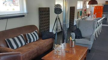 Een moderne woonkamer met een bank, fauteuils, een salontafel en een eetgedeelte met stoelen.