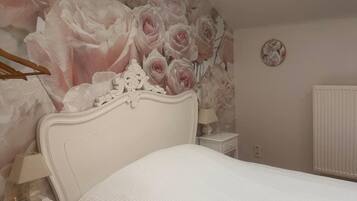 Een slaapkamer met een bed, nachtkastje, lamp, radiator en dakraam.