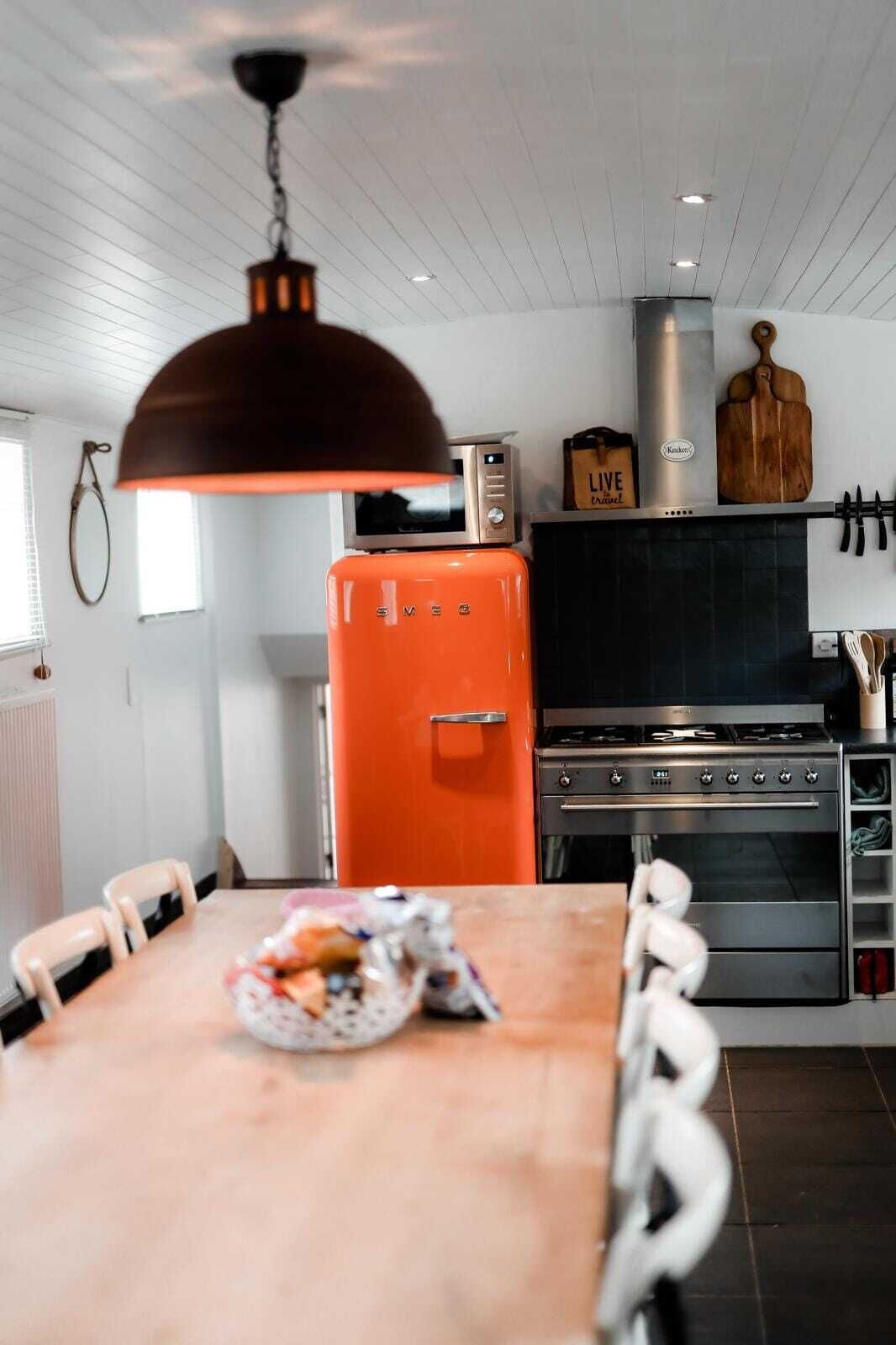 Een keuken met een houten tafel, een rode koelkast en een fornuis.