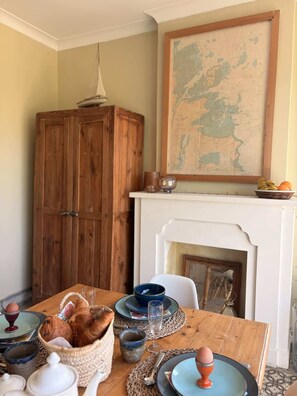 A dining area with a wooden table set for a meal, a wooden cabinet, and a map on the wall.