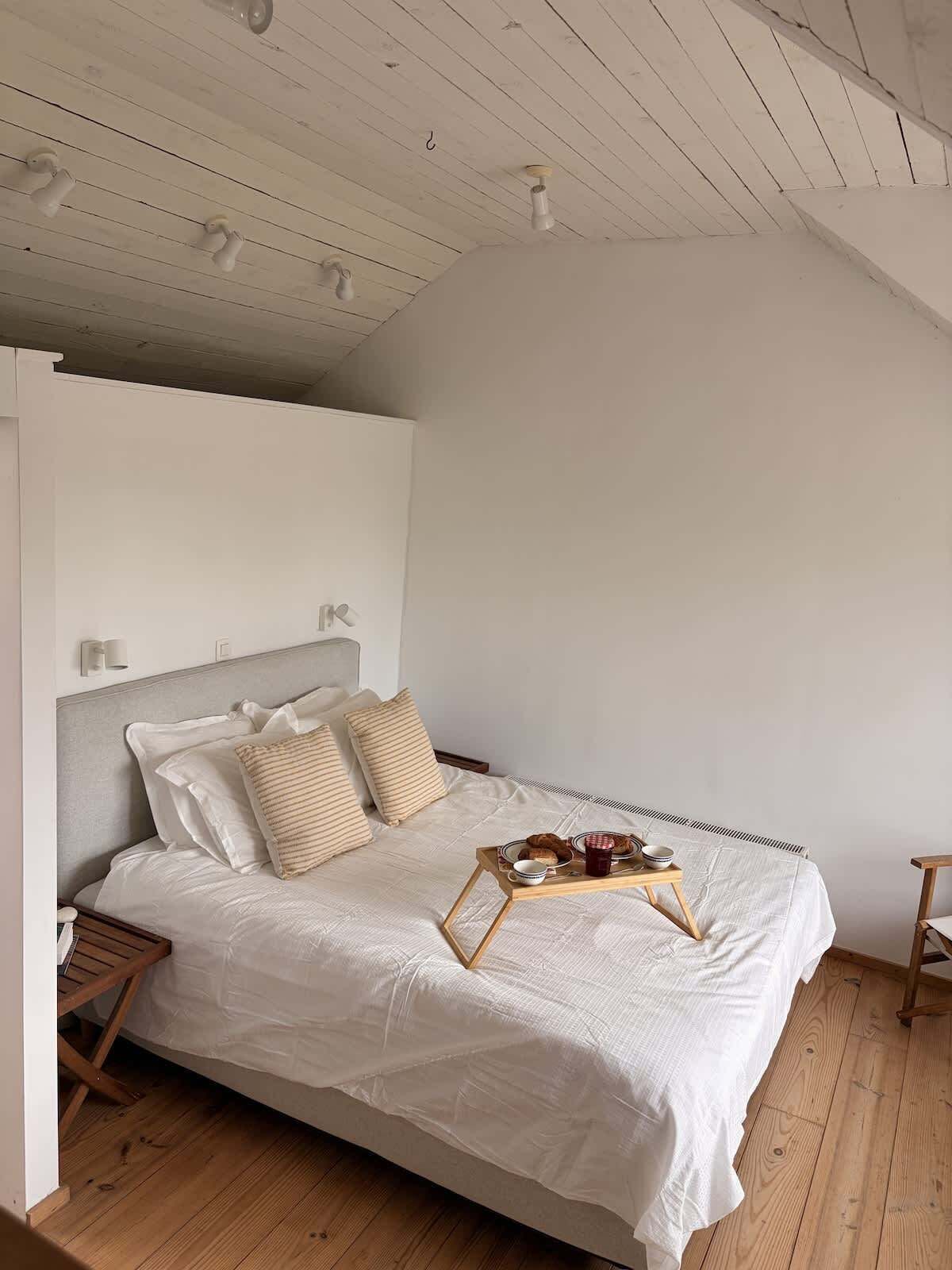 Une chambre à coucher avec un lit, des tables de chevet, un plateau avec de la nourriture et un plancher en bois.