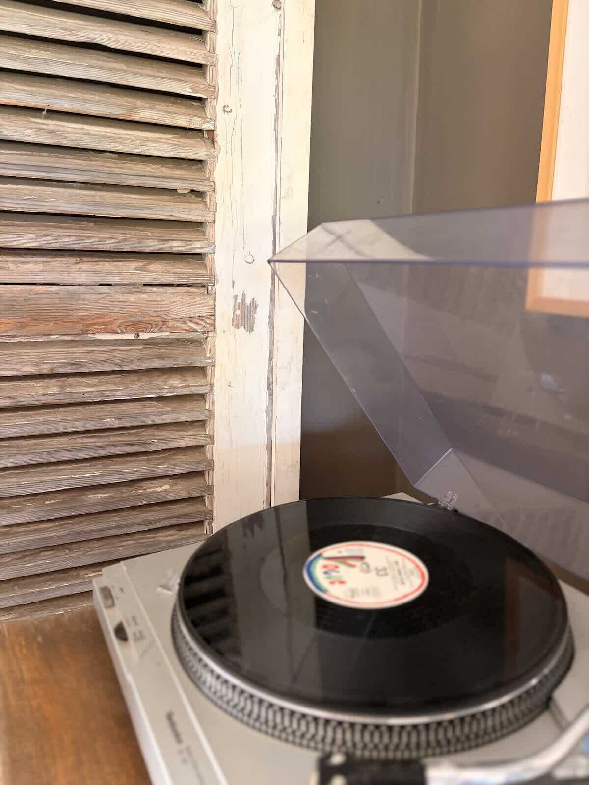 A turntable with a record on it, placed on a wooden surface.