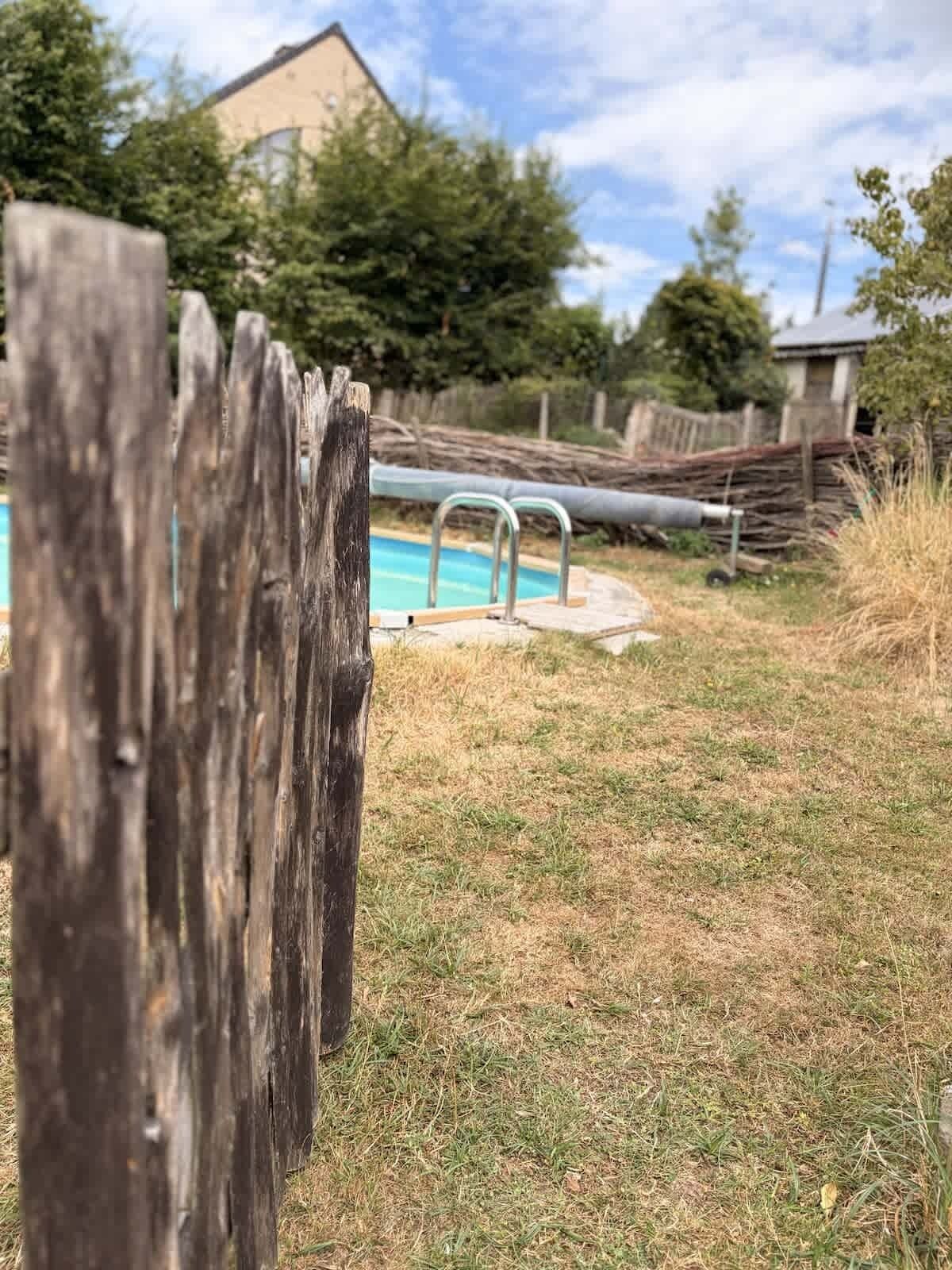 Una valla de madera al frente y una piscina al fondo.