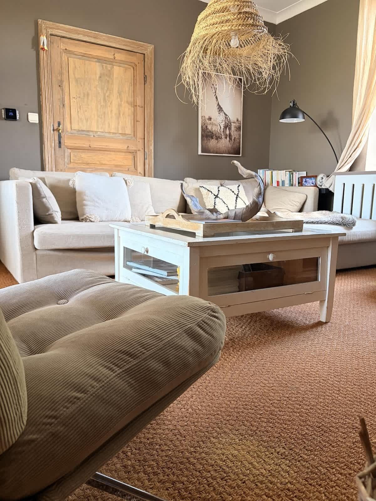 Ein Wohnzimmer mit einer Couch, einem Couchtisch, einer Hängeleuchte und einer großen Holztür.