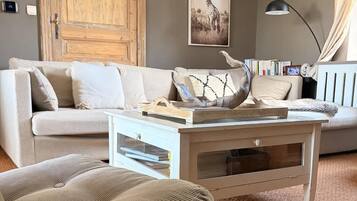 Ein Wohnzimmer mit einer Couch, einem Couchtisch, einer Hängeleuchte und einer großen Holztür.