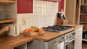 Una cucina con piano cottura a gas, forno e un bancone in legno con una ciotola di frutta.