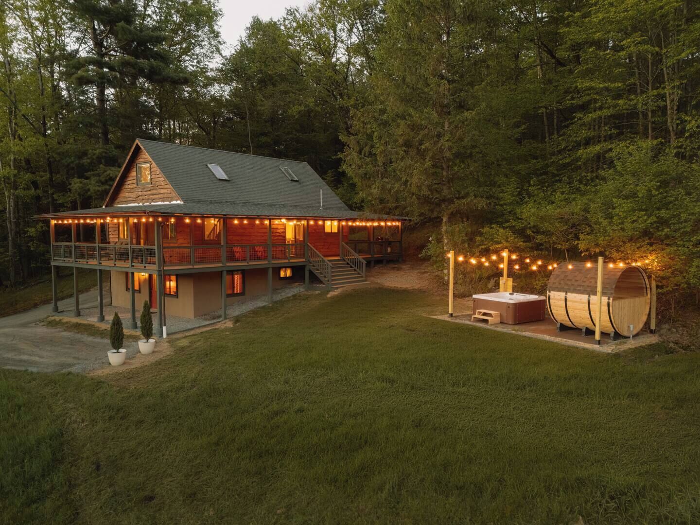 A cabin with a covered porch, a hot tub, and string lights.