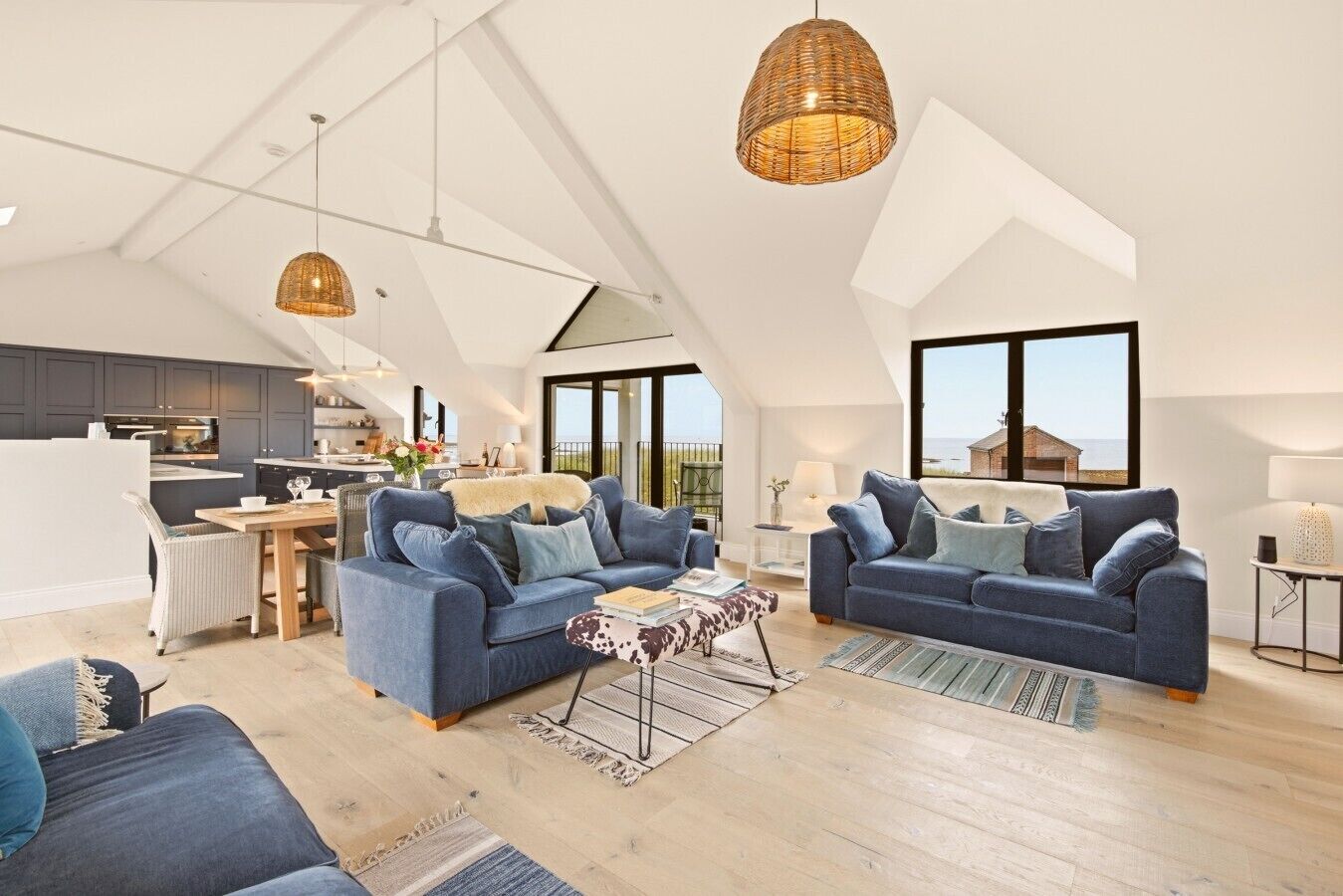 Een ruime loft met hoge plafonds, een keuken, twee banken en grote ramen met uitzicht op zee.