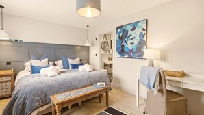 Ein Schlafzimmer mit Bett, Nachttisch, Stuhl, Schreibtisch und Kunstwerk.