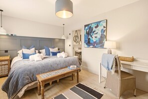 A bedroom with a bed, bedside table, chair, desk, and artwork. - Seaside House - North East Escapes (Beadnell)