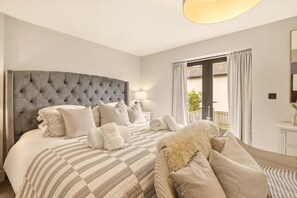 Une chambre d’hôtel avec un grand lit, une tête de lit capitonnée et une vue sur l’extérieur par une fenêtre.